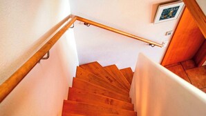 Eine Holztreppe mit Handlauf, weißen Wänden und einem Bild an der Wand.
