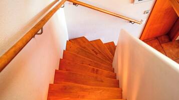 Un escalier en bois avec une rampe, des murs blancs et un tableau accroché au mur.