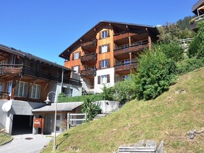 Edifici de fusta de diversos pisos amb balcons, un telefèric i una vessant de pendent coberta d'herba.