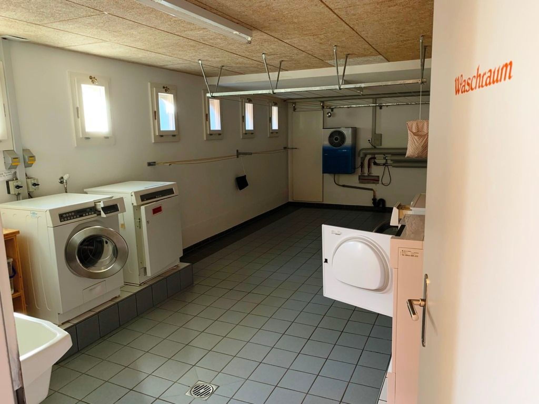 Une buanderie équipée de machines à laver, d’un sèche-linge et d’un système de ventilation.