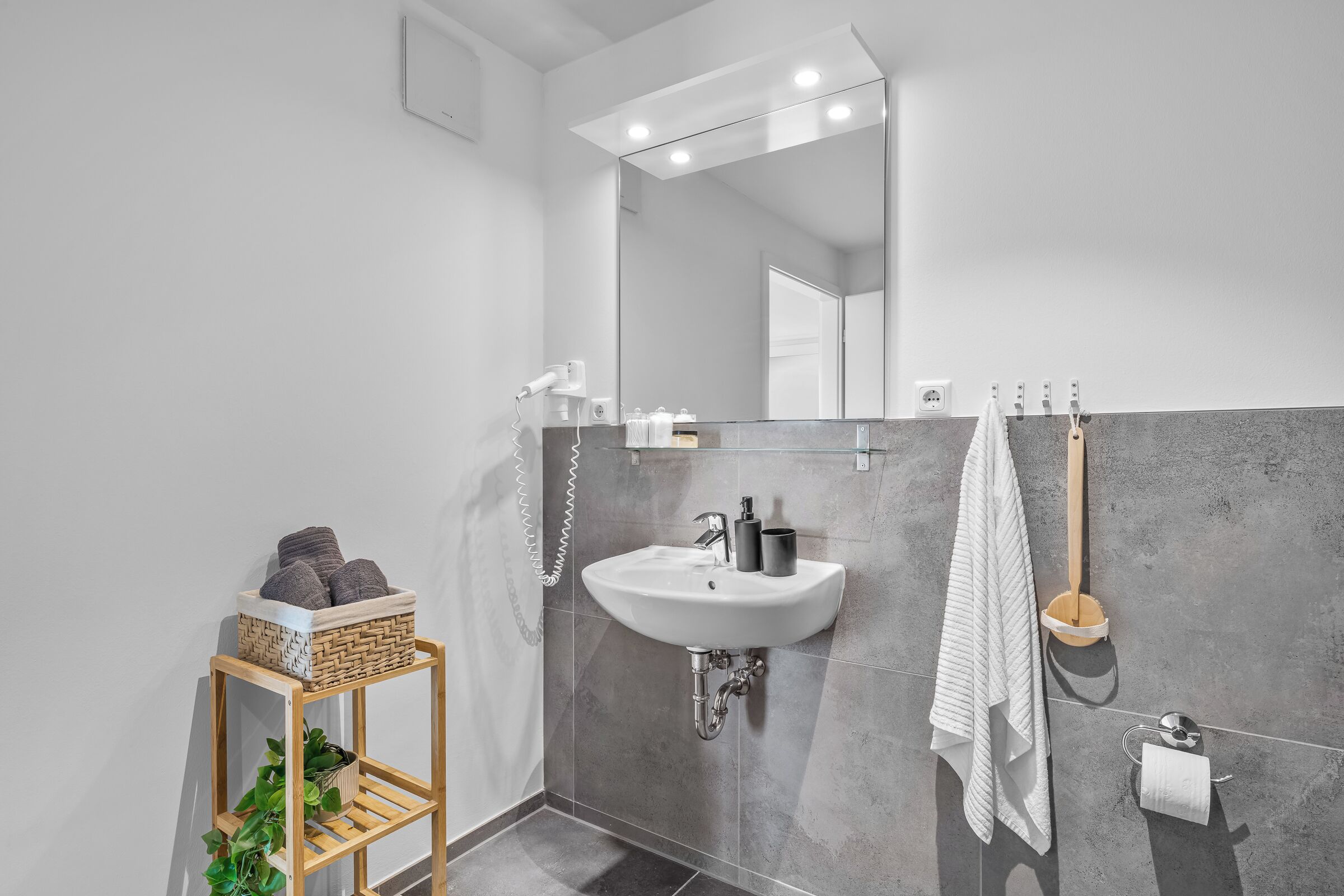 Ein modernes Badezimmer mit Waschbecken, Spiegel und Handtuchhalter in Weiß.