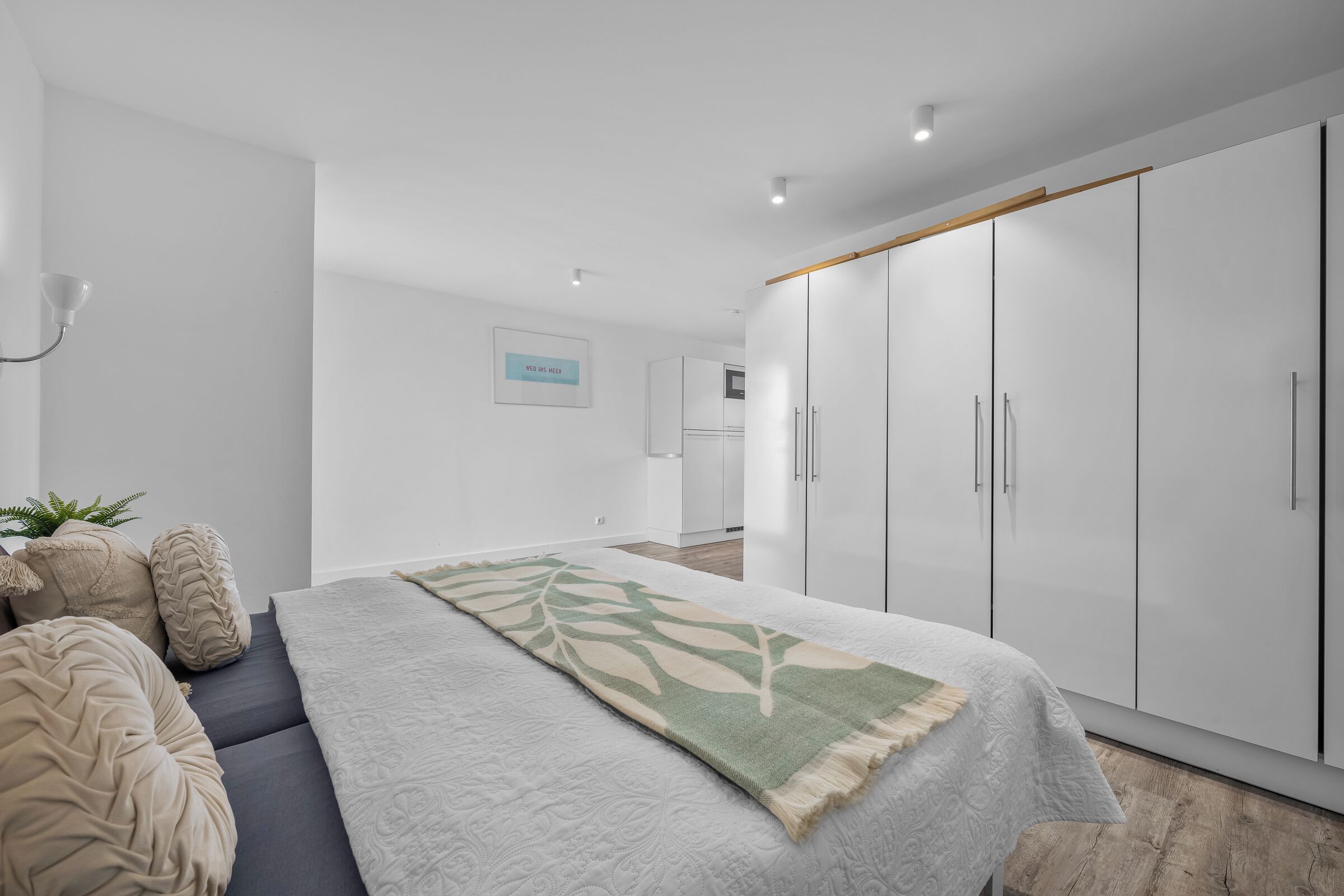 A modern bedroom with a bed, a large wardrobe, and a small seating area.