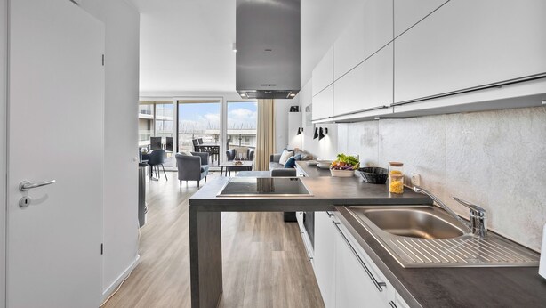 Una cocina moderna con una isla central, electrodomésticos de acero inoxidable y vistas a un comedor.