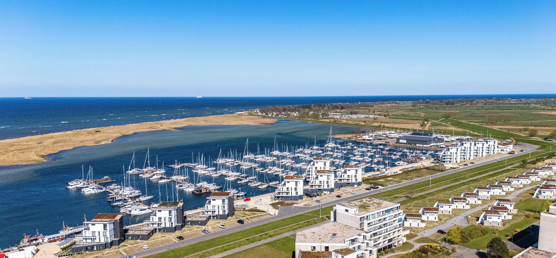 A marina with numerous boats, a coastal road, and residential buildings.