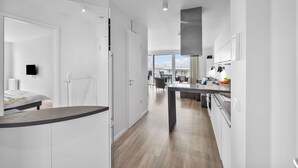 Una cocina moderna con armarios blancos, una isla central y vista al área de estar.