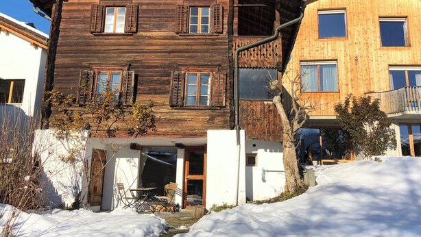 Un chalet en bois doté d’un balcon, d’une entrée couverte et d’un petit espace extérieur aménagé pour s’asseoir.