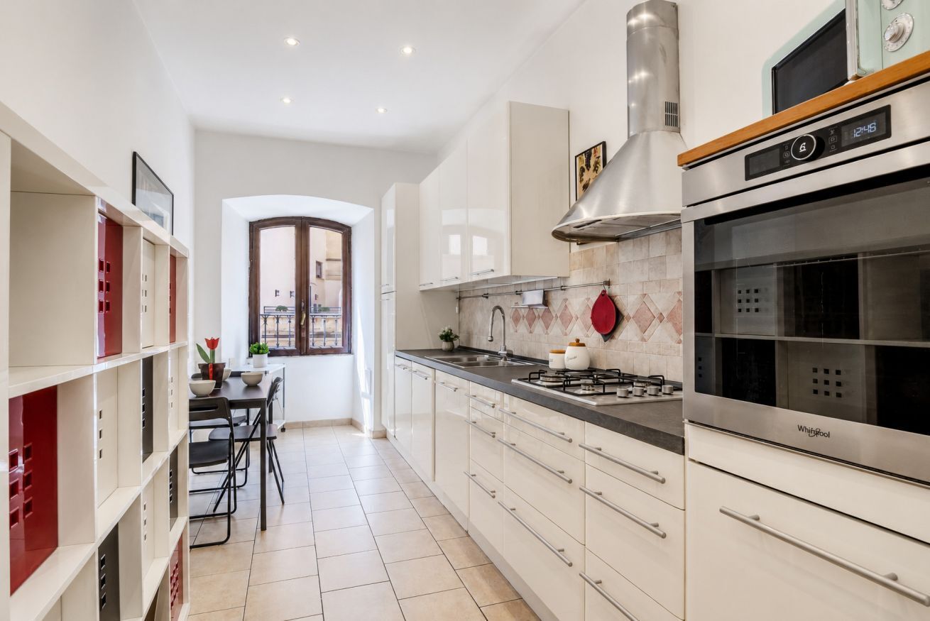 A modern kitchen with white cabinets, a gas stove, an oven, and a window with a view.