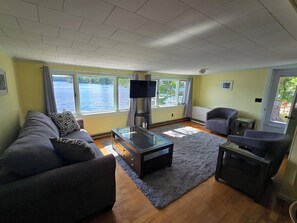 Una sala de estar con sofá, sillones, una mesa de centro y televisión.