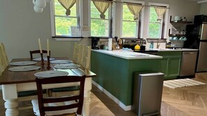 Eine Küche mit Esstisch, Stühlen, einem Kühlschrank und einer Kaffeemaschine.