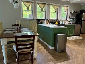 Eine Küche mit Esstisch, Stühlen, einem Kühlschrank und einer Kaffeemaschine.