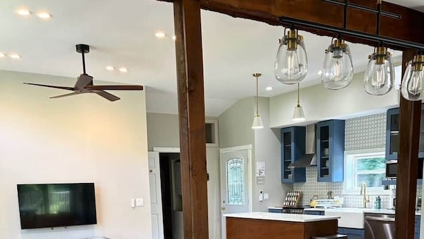 Una cocina moderna con piso de madera, una mesa de comedor con sillas, un sofá y un televisor en una sala de estar.