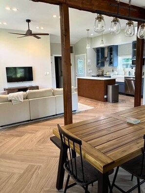 Una cocina moderna con piso de madera, una mesa de comedor con sillas, un sofá y un televisor en una sala de estar.