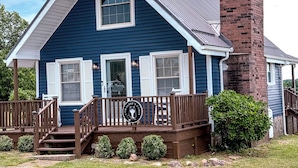 A two-story house with a brick chimney, a porch with a railing, and a small garden area.