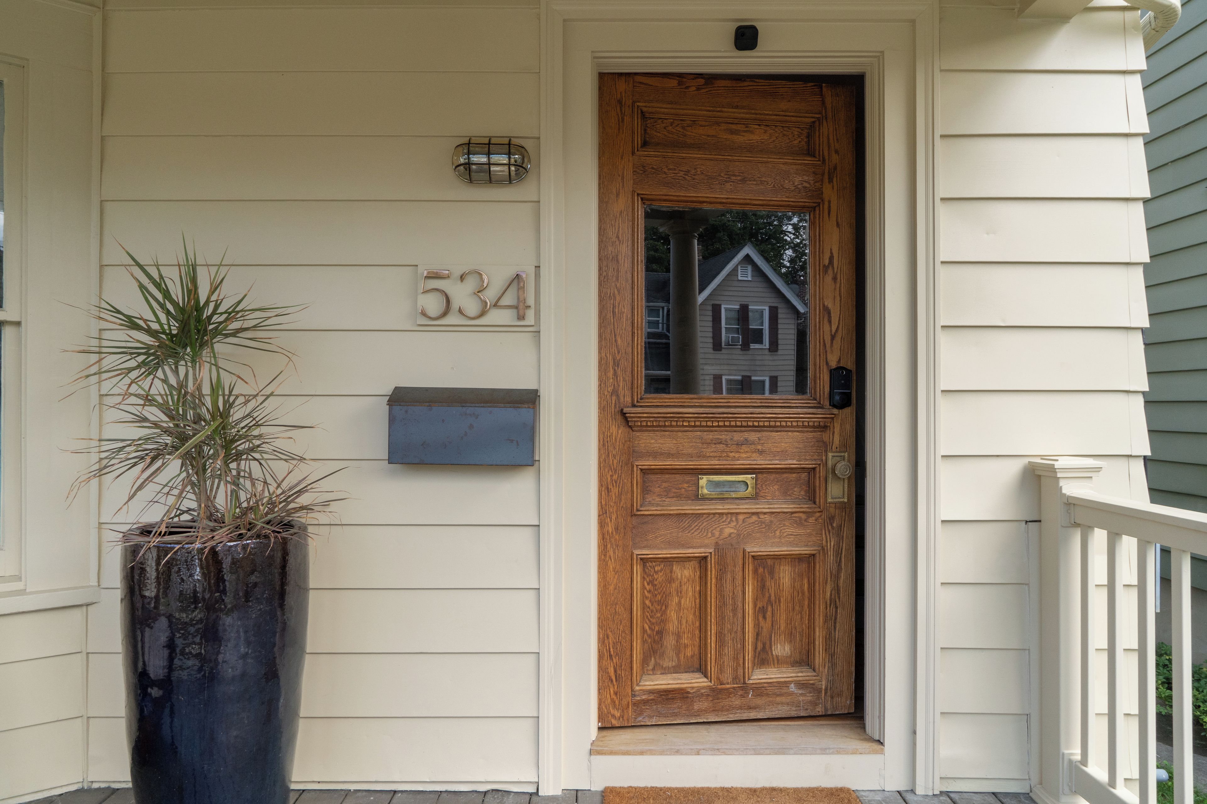 A wooden front door with a mailbox and a house number sign.