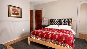A bedroom with a bed, a wooden headboard, a framed picture on the wall, and a door in the background.