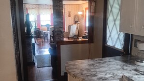 Una cocina con encimera de mármol, refrigerador blanco y mesa de comedor de madera con sillas.