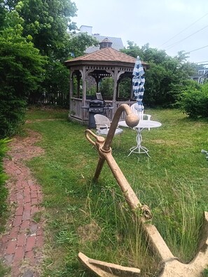 A gazebo with a grill, a white chair, and a table with a checkered umbrella. - Beach 5 min walk Ocean view Spacious 3-bedroom apartment in Hyannis with AC (Barnstable)
