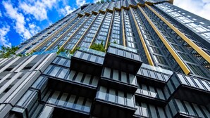 En høj bygning med et moderne arkitektonisk design, der har en række balkoner og store vinduer.