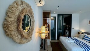 Et moderne hotelværelse med et stort spejl, en sengetavsalampe, en seng med blåt og hvidt sengetøj og et garderobeskab.