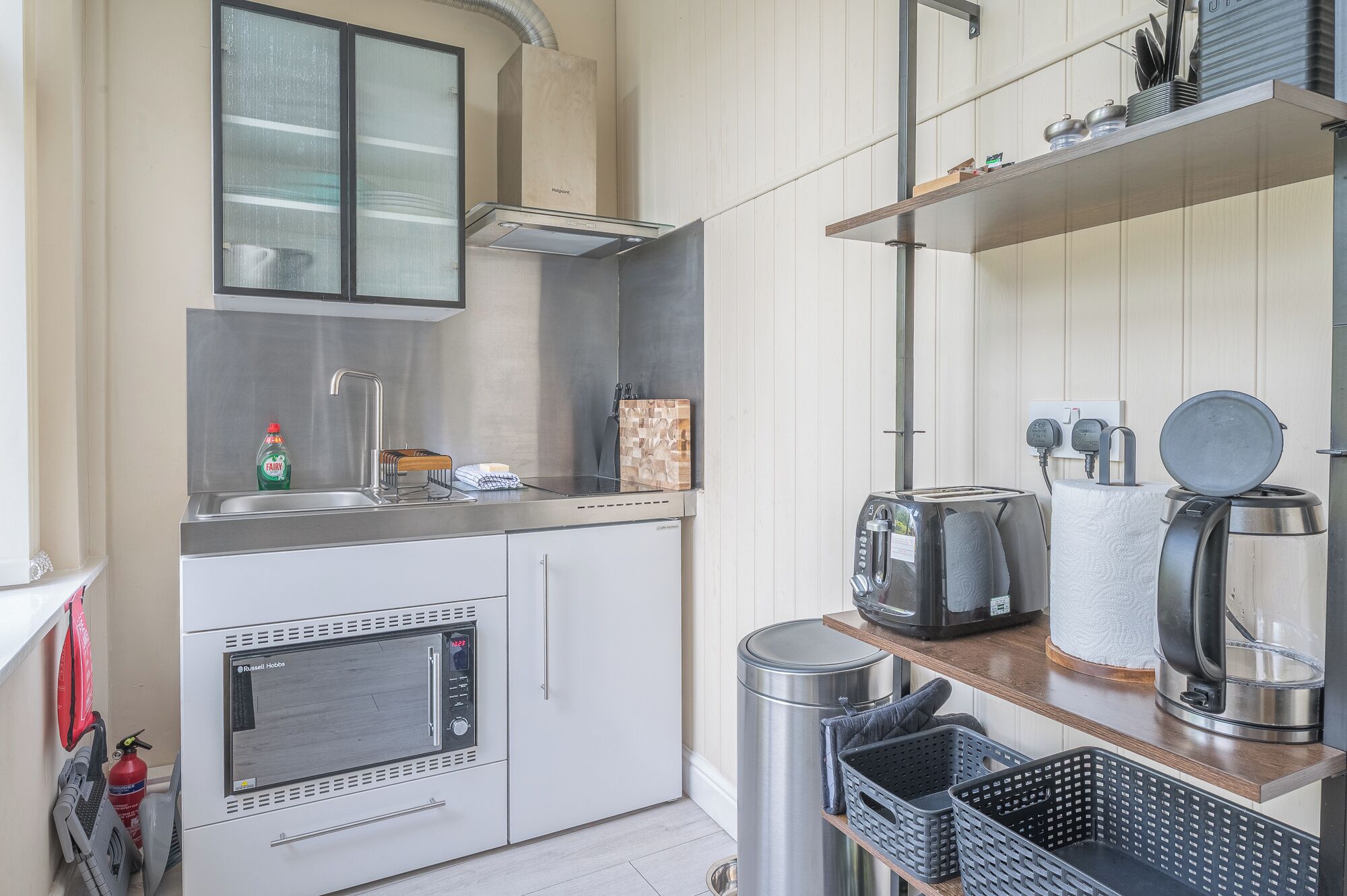 A compact kitchenette with a microwave, toaster, kettle, and a small sink.