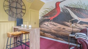 Habitación con un mural de aves, una barra de madera y una alfombra roja.