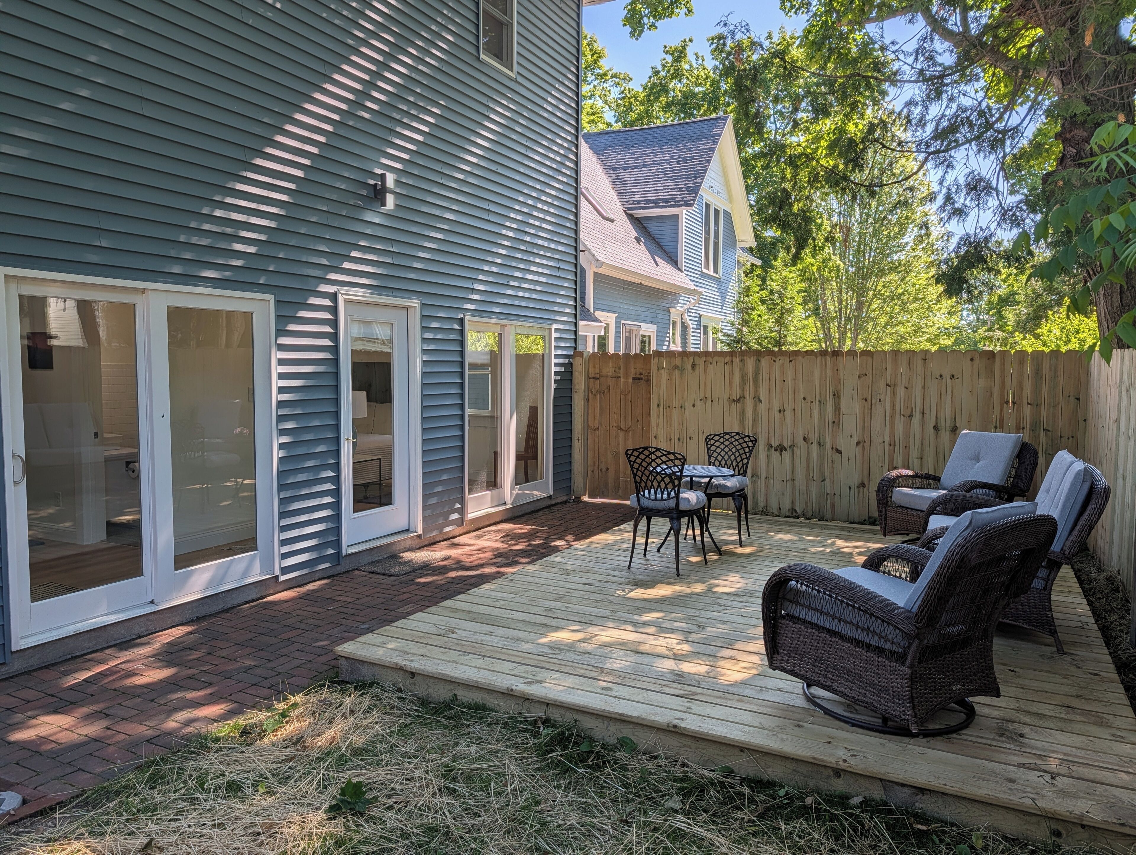 Une maison avec une terrasse, des portes-fenêtres coulissantes et du mobilier d’extérieur.