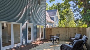 Une maison avec une terrasse, des portes-fenêtres coulissantes et du mobilier d’extérieur.