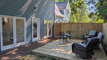 Une maison avec une terrasse, des portes-fenêtres coulissantes et du mobilier d’extérieur.