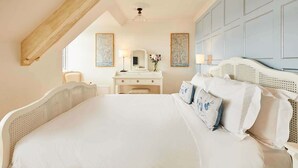 A bedroom with a large bed, a dresser, a vanity, and two wall-mounted paintings. - Host Stay The Nest Whitby (Whitby)