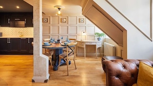 A modern kitchen with dark cabinets, a herringbone backsplash, and a dining area with a wooden table and chairs. - Host Stay The Nest Whitby (Whitby)