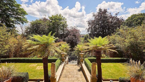 A stone pathway leading to a gate, surrounded by lush greenery and trees. - Host Stay The Nest Whitby (Whitby)