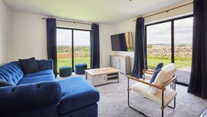 Ein modernes Wohnzimmer mit einem Ecksofa, einem Sessel, einem Couchtisch und einem Flachbildfernseher.