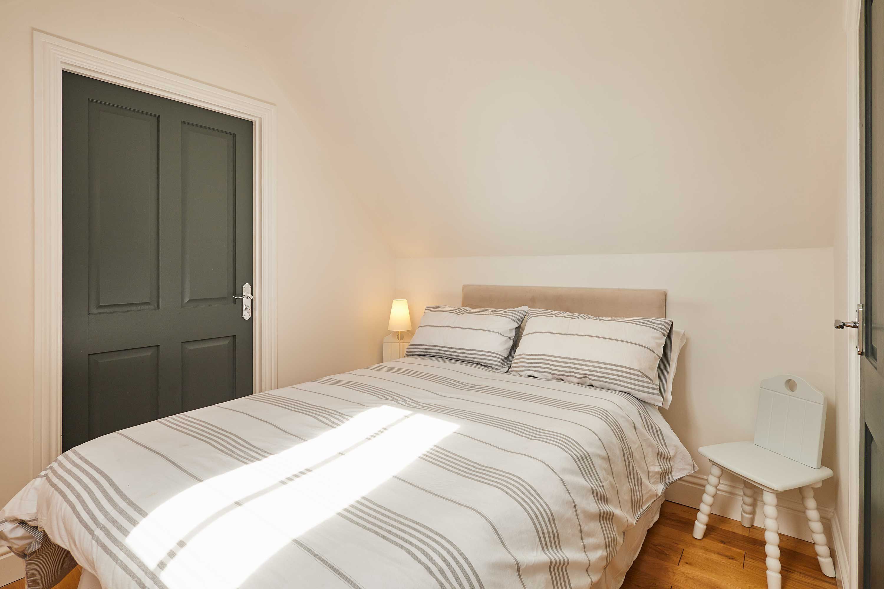 Una camera da letto con un letto, un comodino, una lampada e una porta.
