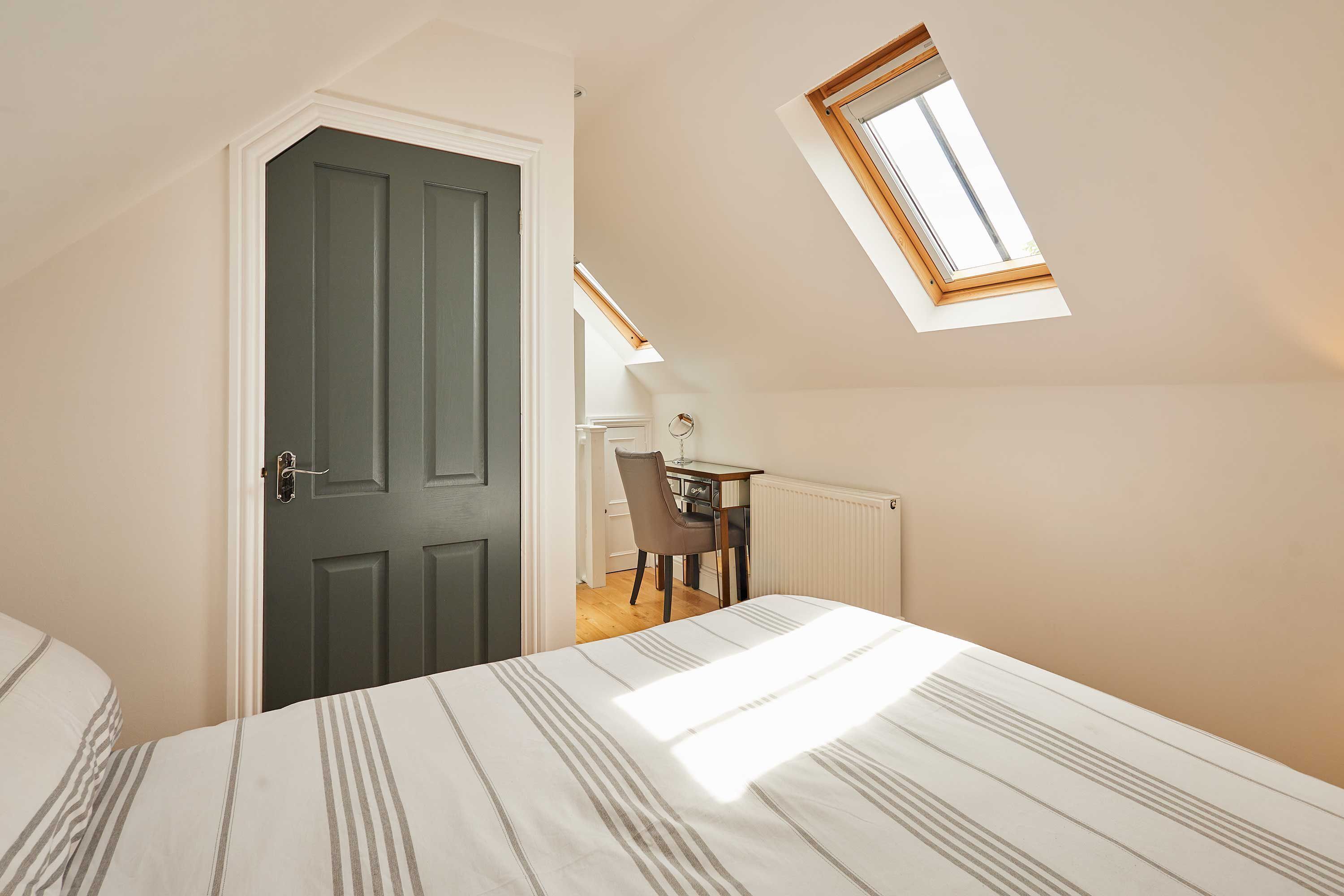A bedroom with a bed, a desk, and a chair.