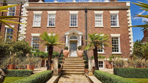 A brick building with a central entrance, steps leading up to it, and potted plants around. - Host Stay The Chimneys Whitby (Whitby)