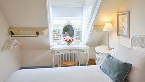 A bedroom with a bed, a vanity with a mirror, a window, and a lamp. - Host Stay The Chimneys Whitby (Whitby)