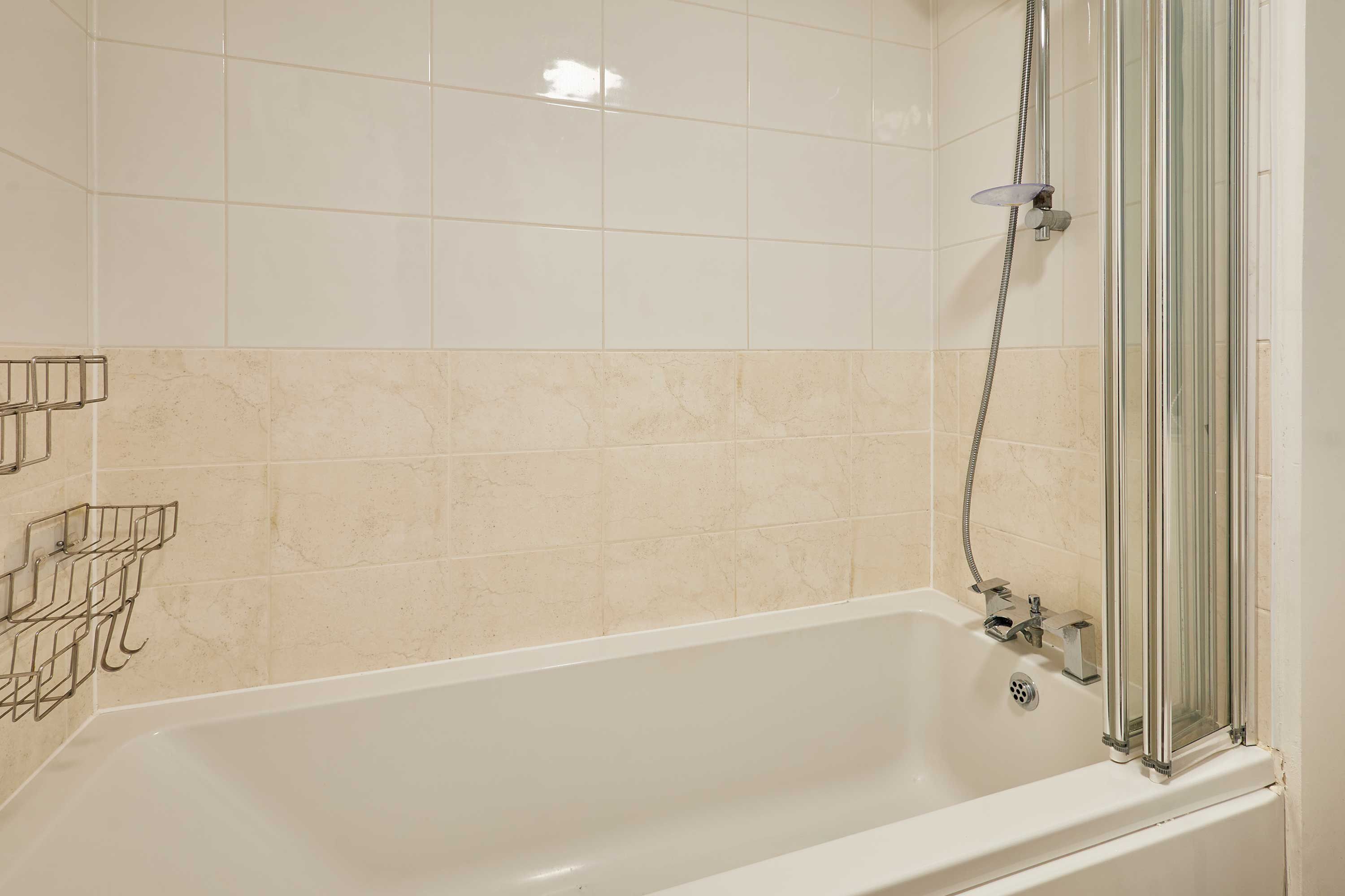 A bathroom with a bathtub, shower, and tiled walls.