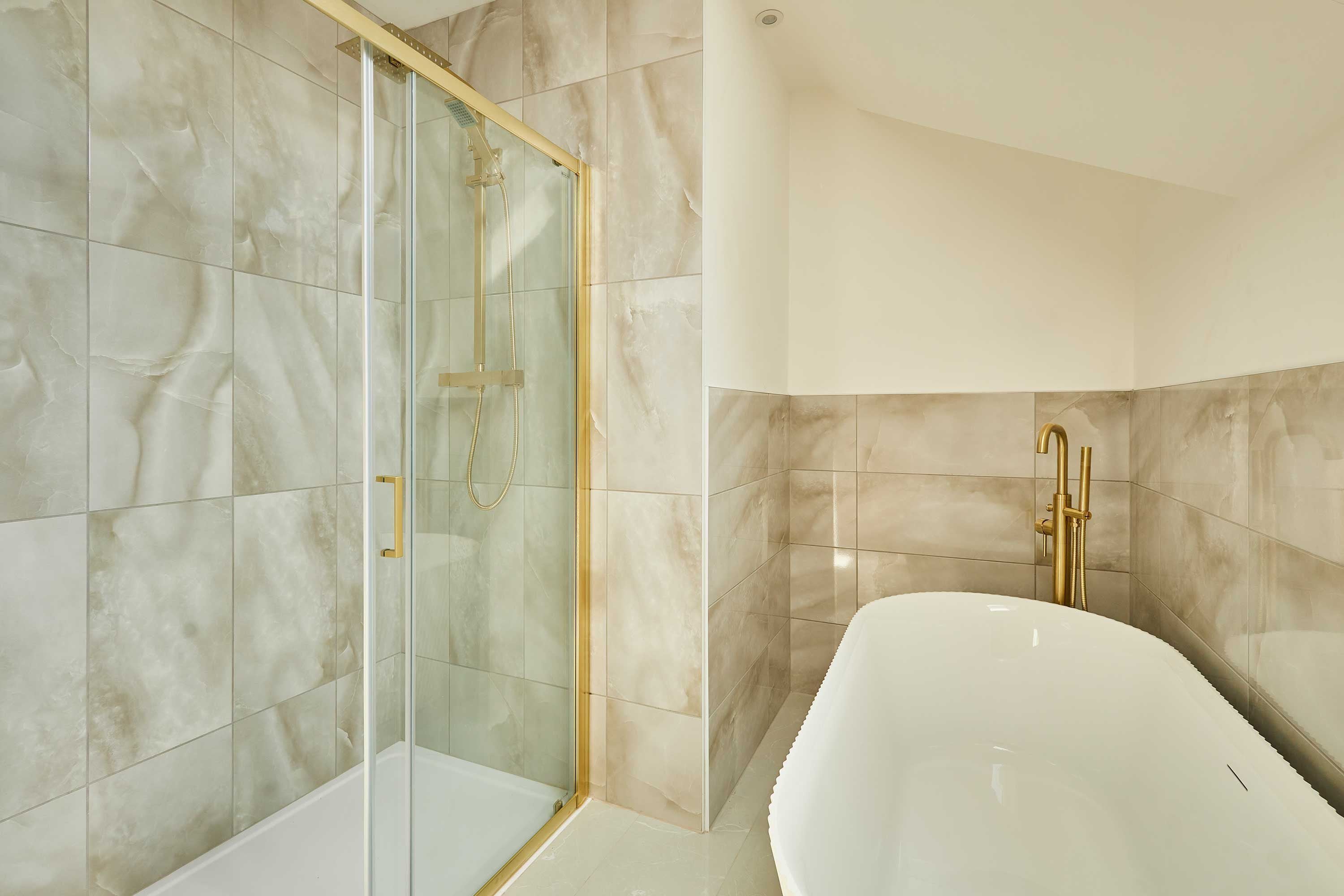 A modern bathroom with a glass-enclosed shower, a white bathtub, and marble tiles.