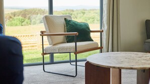A room with a large window, a chair with a cushion, and a round table. - Host Stay Bluebell Cottage (Newcastle-upon-Tyne)