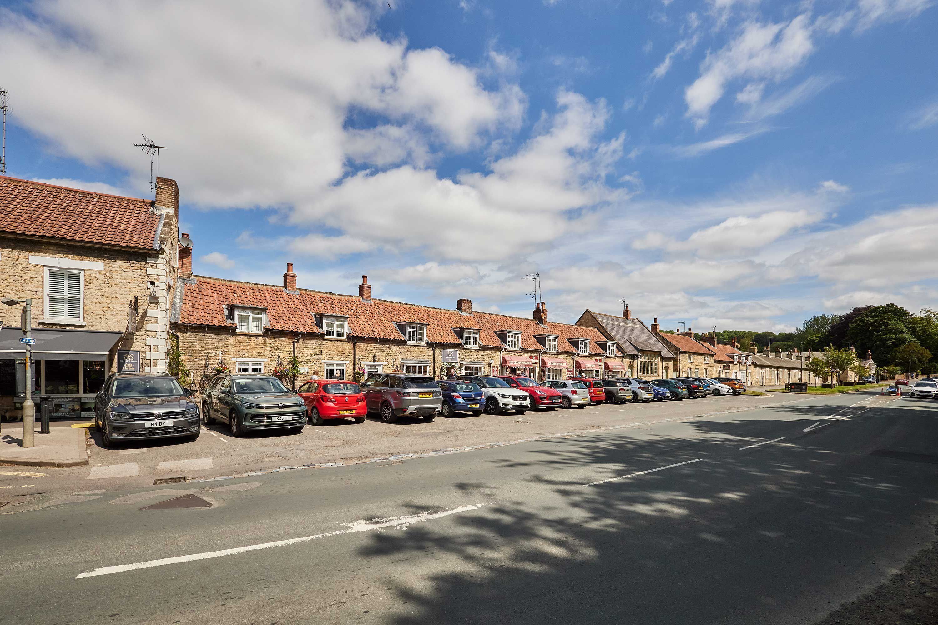 A row of townhouses with parked cars along a street.