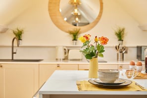A kitchen with a central island, a round mirror, and a vase with flowers. - Host Stay Topsail (Whitby)