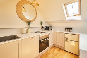 A compact kitchen with a sink, microwave, stove, and refrigerator. - Host Stay Topsail (Whitby)