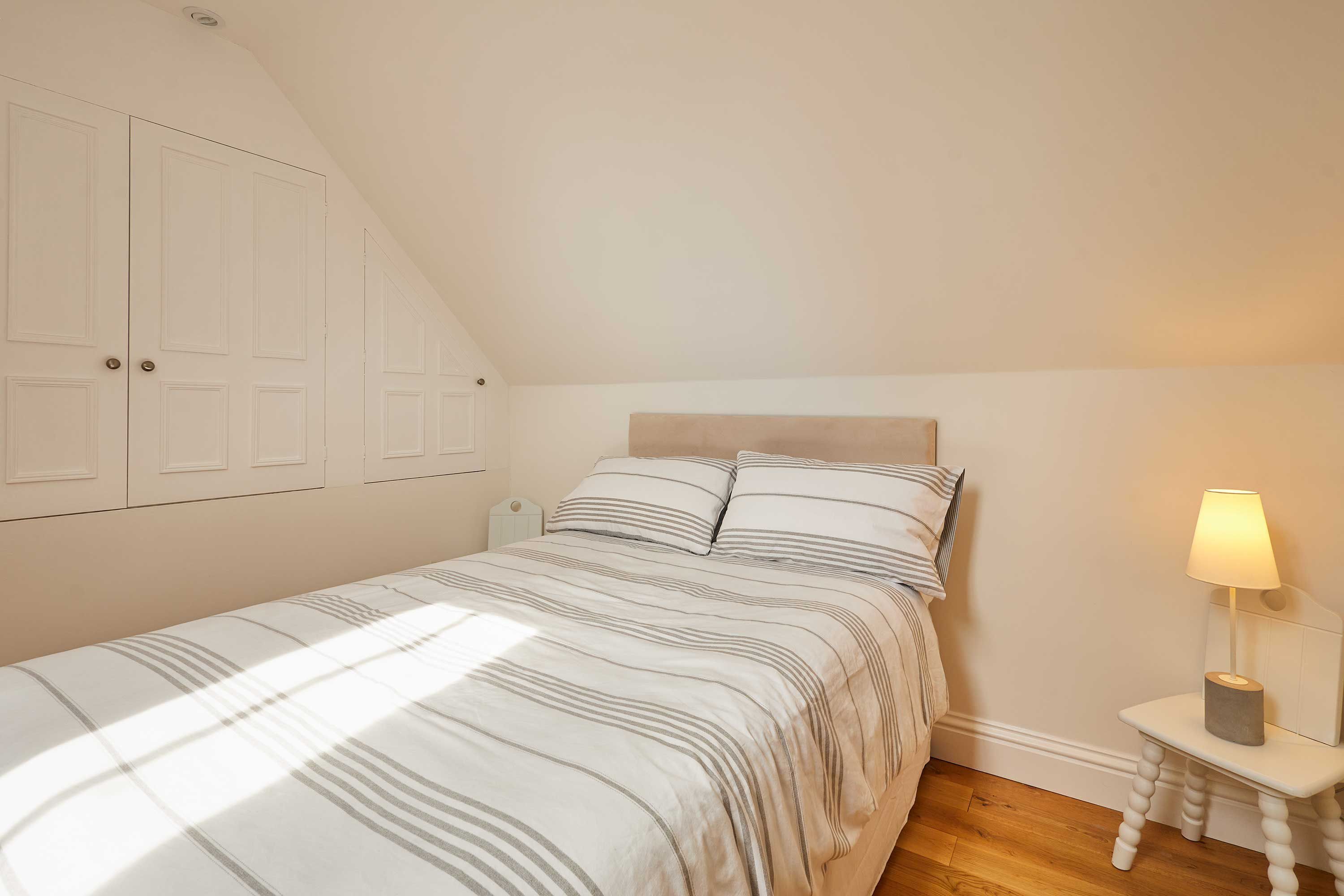 Une chambre à coucher avec un lit, une table de chevet, une lampe et une armoire.