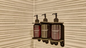 Un baño con pared texturizada y tres botellas de productos Wynwood*.