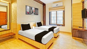 Ett hotellrum med två sängar, en stor spegel, ett fönster med persienner och en väggmonterad luftkonditioneringsanläggning.