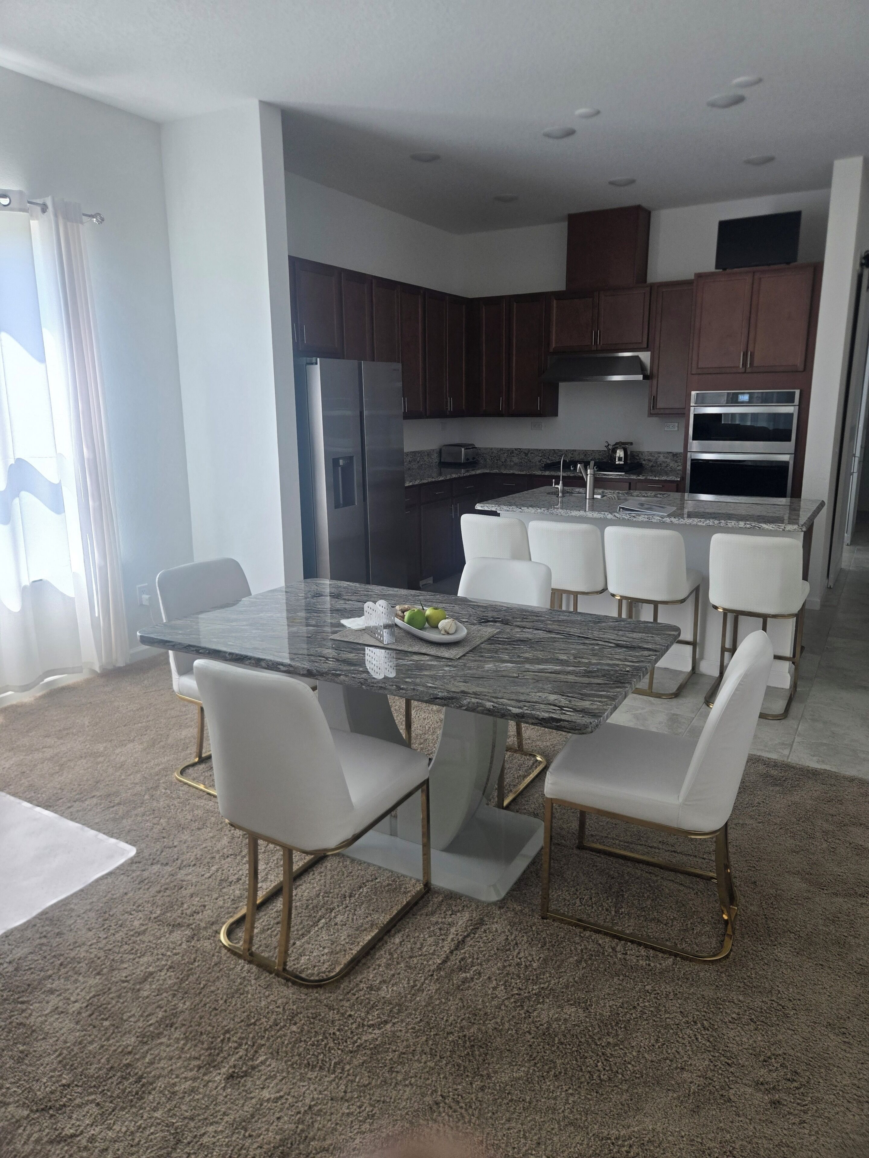 A modern kitchen with dark wood cabinets, stainless steel appliances, and a marble countertop.