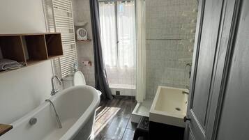 Une salle de bain avec une baignoire, un lavabo et un espace douche.