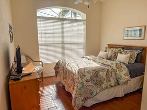 A bedroom with a bed, a desk, and a window with blinds. - Villa Vito, Gulf Access, Pool, Dock & Office (Cape Coral)