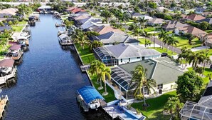 Un quartiere residenziale con un canale, case dotate di pannelli solari e una barca ormeggiata sulla riva.