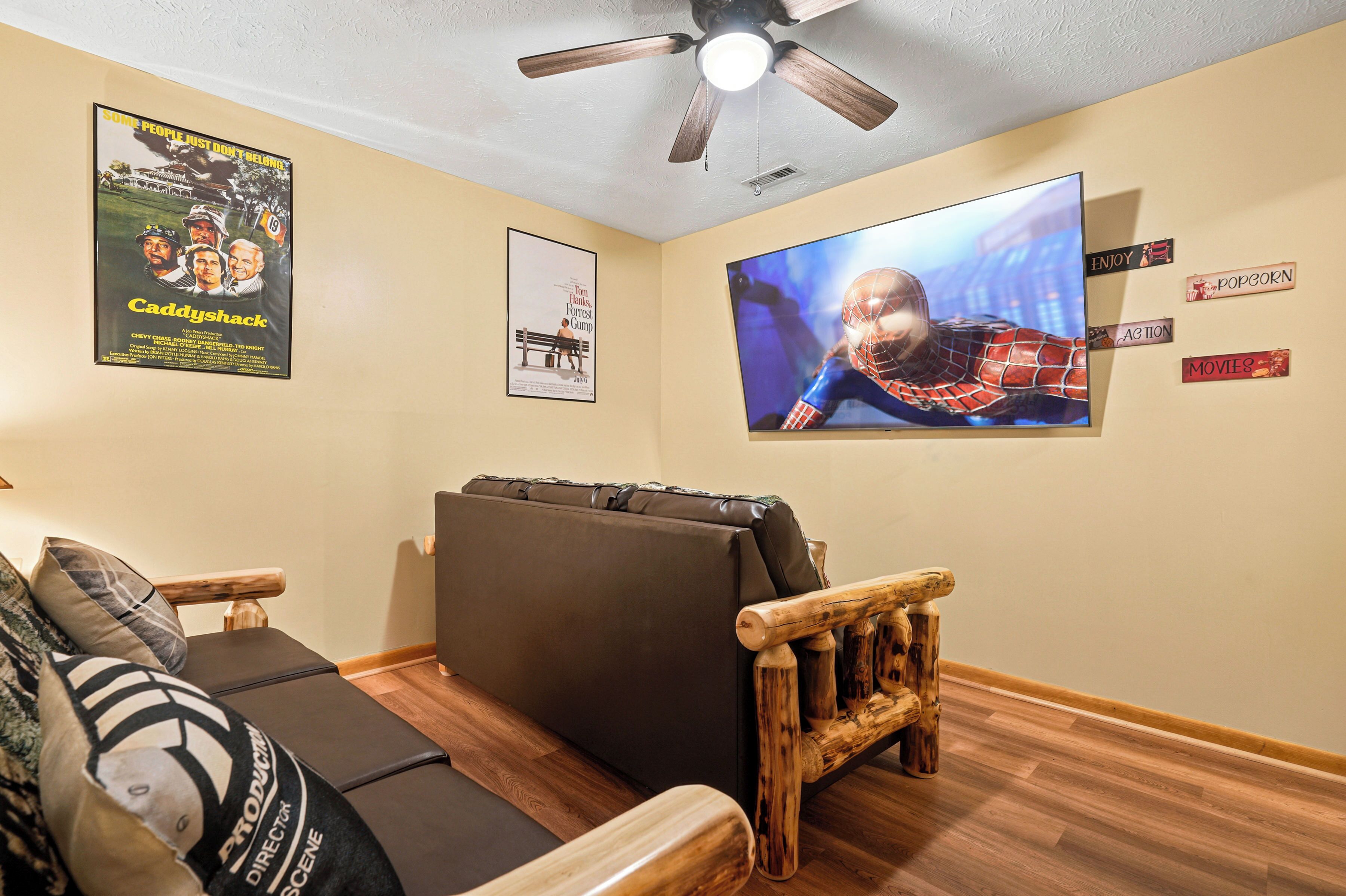 Una habitación con ventilador de techo, televisor de pantalla plana grande, sofá y una silla de madera.